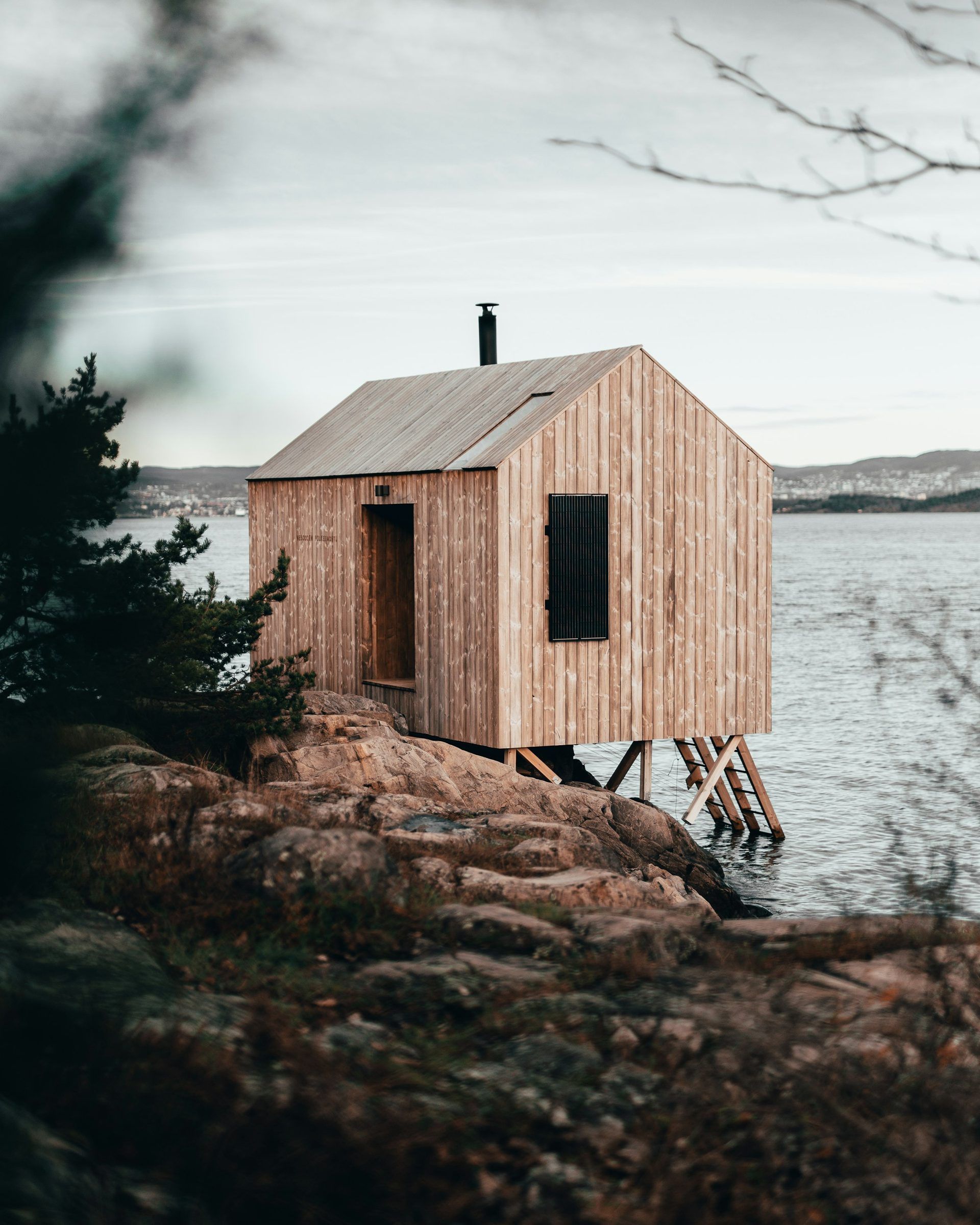 En liten trebadstue på et svaberg ved sjøen.